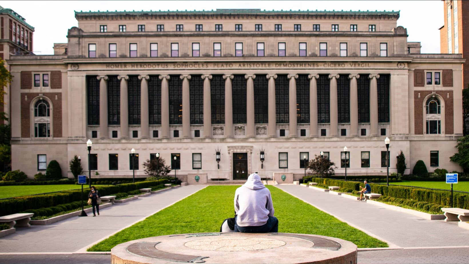 A person sitting in front of Columbia University and reading about NYC's tech ecosystem.