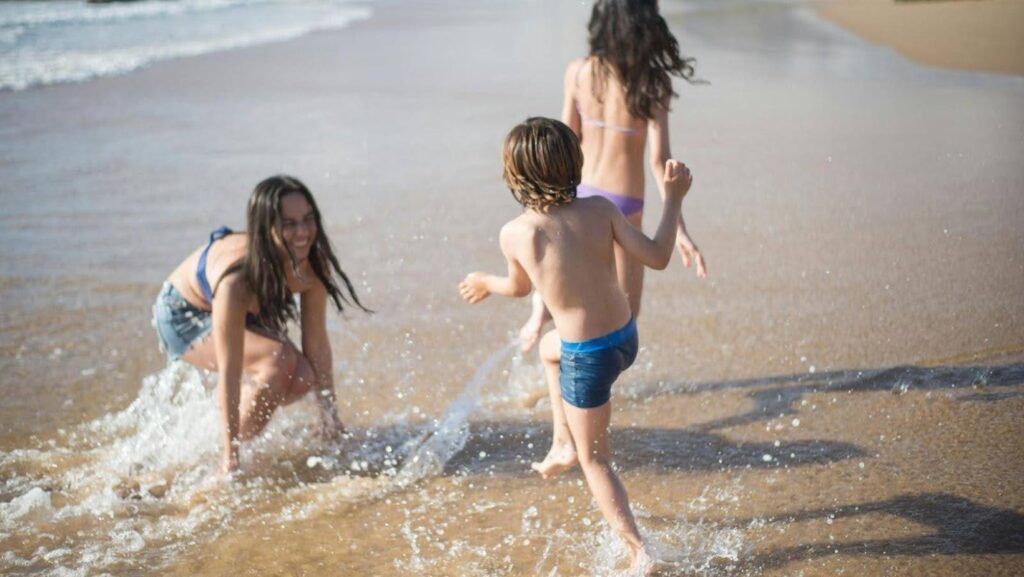 three children playing on the shore of a beach
