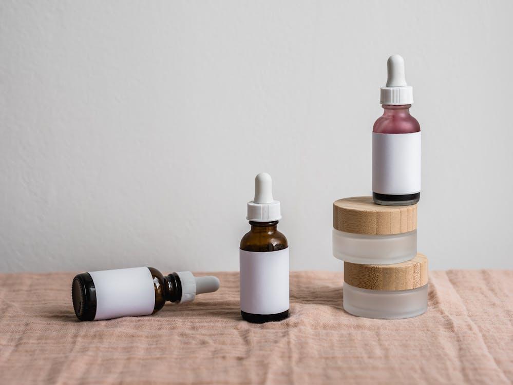 Free Minimalist display of assorted dropper bottles with blank labels on linen surface. Stock Photo