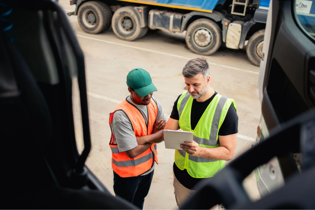 Truck drivers reviewing documents, highlighting the operational challenges faced by Canadian trucking companies due to U.S. regulations